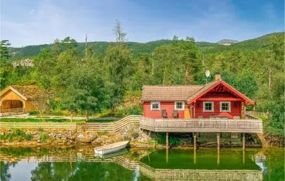 a red cabin on the water with a boat at 3 Bedroom Amazing Home In Sandane in Sandane