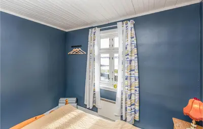 a bedroom with blue walls and a window at Holiday Home Kvamsøy Storholmen in Sandvik