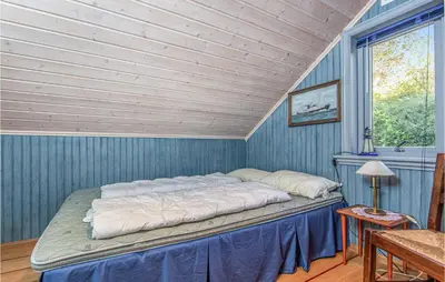 a bed in a room with a blue wall at Beautiful Home In Hundeidvik in Hundeidvik