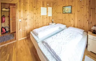 a bedroom with a large bed in a wooden wall at Hytte 19 in Ikornnes