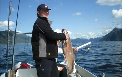 a man holding a large fish on a boat at Hytte 19 in Ikornnes