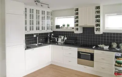 a kitchen with white cabinets and black tiles at Sandshamn in Sandshamn