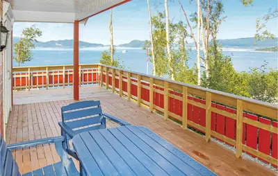 a blue bench on a porch with a view of the water at 4 Bedroom Beautiful Home In Hundeidvik in Hundeidvik