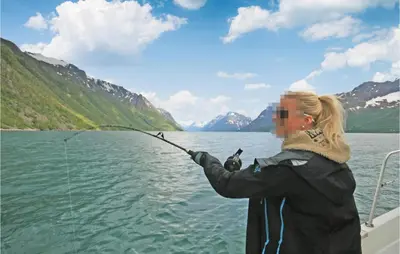a woman fishing on a boat on a lake at Gorgeous Home In Hundeidvik in Hundeidvik