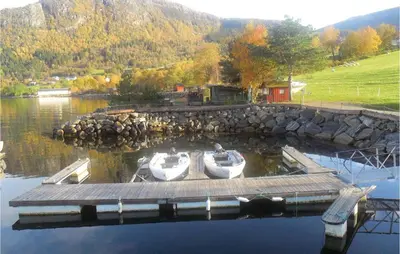two boats are docked at a dock on a lake at Holiday Home Vågstranda Hjelvik Ii in Hjelvik