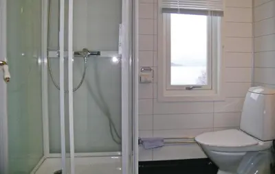 a bathroom with a shower and a toilet and a window at Lovely Home In Vågstranda in Hjelvik
