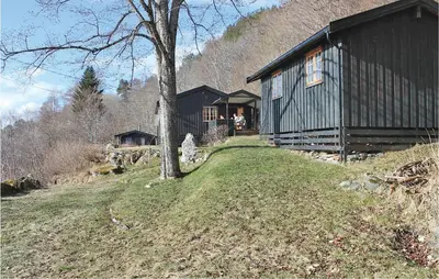 a black house on a hill next to a tree at Idavolden in Stangvik