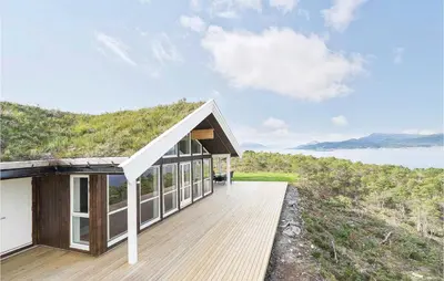 a house with a wooden deck next to a body of water at 4 Bedroom Lovely Home In Kvisvik in Kvisvik