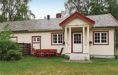 a small white house with a red bench in the yard at Amazing Home In Ringebu in Ringebu