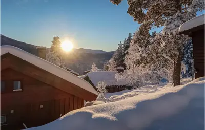 a snow covered house with the sun in the background at Holiday Home Heidal Bakketun in Heidal
