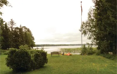 a bench sitting in the grass near a lake at Kveldsro in Eina