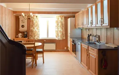 a kitchen with wooden cabinets and a table and a window at 3 Bedroom Amazing Home In Vestsida in Fall