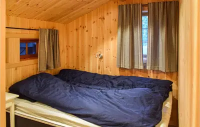 a bedroom with a blue bed in a wooden wall at Holiday Home Sjusjøen Tyrily in Sjusjøen