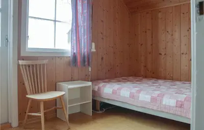 a bedroom with a bed and a chair and a window at Lovely Home In Vestsida With Wifi in Fall