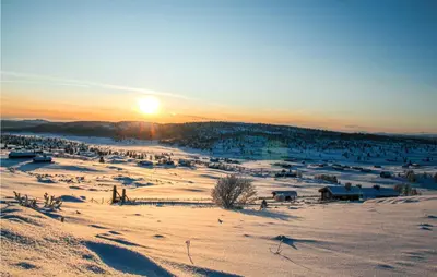 a snowy field with the sun setting in the background at Holiday Home Ringebu Måsåplassen Ii in Ringebu
