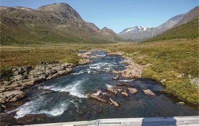 a river in a field with mountains in the background at Thorleifsbuskogheim in Vang I Valdres