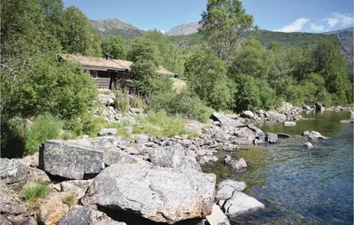 a river with rocks in front of a house at Holde in Hemsedal