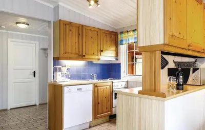 a kitchen with wooden cabinets and a white dishwasher at Vinjebu in Hemsedal