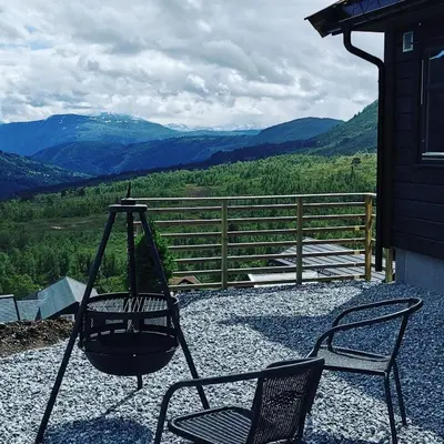 two chairs and a swing on a porch with mountains at Mlodge - The Mountain Lodge in Sogndal