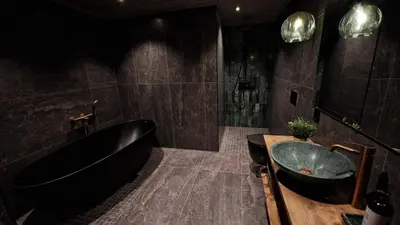 a bathroom with a black tub and a sink at Mlodge - The Mountain Lodge in Sogndal