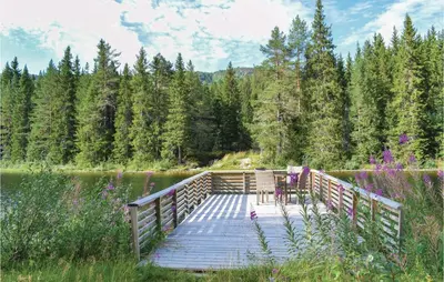 a wooden bridge over a lake with two chairs on it at Sundflathytta in Nesland