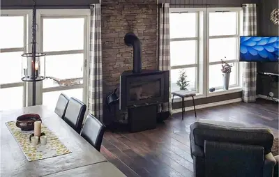 a living room with a fireplace and a dining room table with a wood stove at Lovely Home In Rauland With Sauna in Rauland