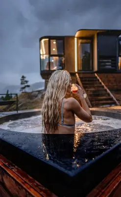 a woman sitting in a hot tub with a drink at Sogndal Fjordpanorama - The atmosphere in Sogndal