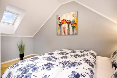 a bedroom with a bed and a painting on the wall at Dragesmauet Apartments in Bergen
