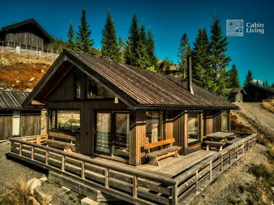 a large wooden cabin with a large deck at New large cabin Ski in out Sjusjøen & sauna in Ringsaker