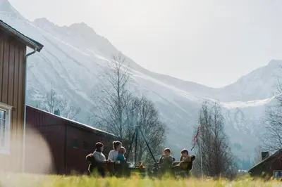 a group of people standing outside a building with mountains in the background at Lensmansgarden Fjøsen in Innfjorden