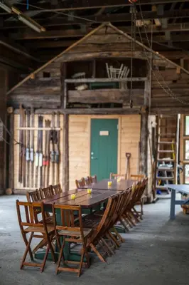 a wooden table and chairs in a room with a green door at Lensmansgarden Fjøsen in Innfjorden