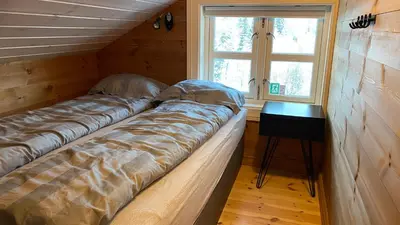 two beds in a room with a window and a table at Penthouse by the ski lift, 4 bedrooms, 2 living rooms in Stranda