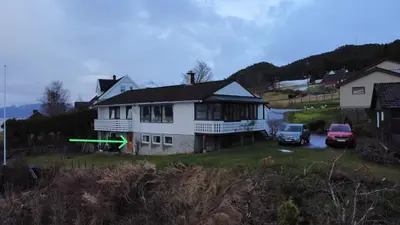 a house with a car parked in front of it at Fjord side apartment in Jondal