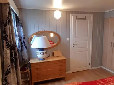 a bedroom with a lamp on a dresser with a mirror at Fjord side apartment in Jondal