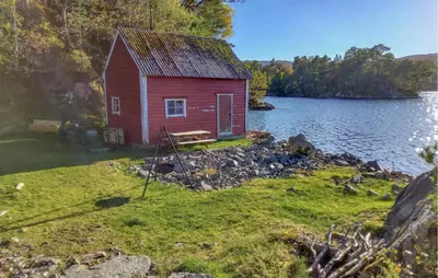 a small red house on the shore of a lake at Gorgeous Home In Reksteren With Kitchen in Hope