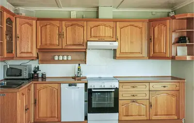 a kitchen with wooden cabinets and a white stove top oven at Lovely Home In Fjelberg With Wifi in Sæbø