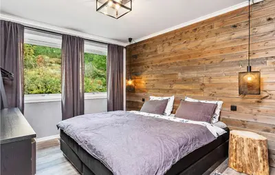 a bedroom with a wooden accent wall and a bed at Sjøbris in Erve