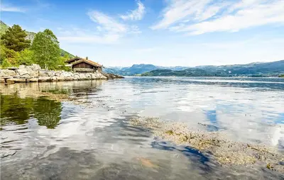 a view of a river with a house in the distance at Sjøbris in Erve
