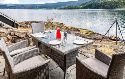 a table and chairs with a table and water at Sjøbris in Erve