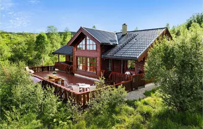 a large wooden house with a deck in a forest at Cozy Home In Norheimsund With Sauna in Norheimsund
