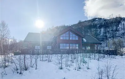 a house in the snow in front of a mountain at Cozy Home In Norheimsund With Sauna in Norheimsund