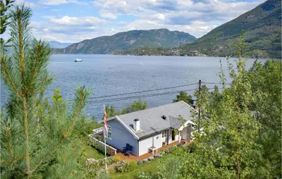 a house on the shore of a large body of water at Beautiful Home In Jondal in Jondal