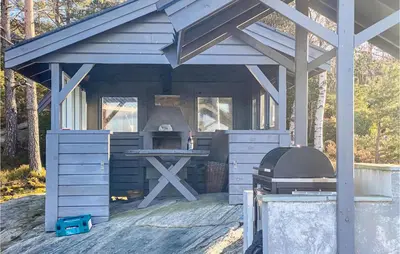 an outdoor kitchen with a picnic table and a grill at 3 Bedroom Stunning Home In Masfjorden in Masfjorden
