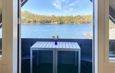 a table on a balcony with a view of a lake at 3 Bedroom Stunning Home In Masfjorden in Masfjorden
