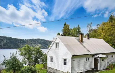 a white house with a lake in the background at Beach Front Home In Tysse With Wifi in Tysse