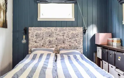 a bedroom with a bed with blue walls and a window at Beach Front Home In Tysse With Wifi in Tysse