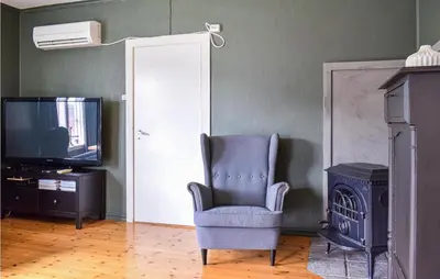 a living room with a chair and a television at Beach Front Home In Tysse With Wifi in Tysse