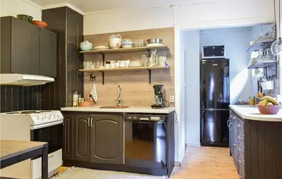 a kitchen with a sink and a black refrigerator at Beach Front Home In Tysse With Wifi in Tysse