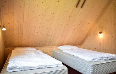 two beds in a room with wooden walls at 2 Bedroom Cozy Home In Stolmen