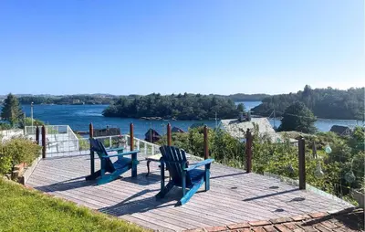 two blue chairs sitting on a wooden deck overlooking a river at Gorgeous Home In Fjell With Wifi in Lokøy